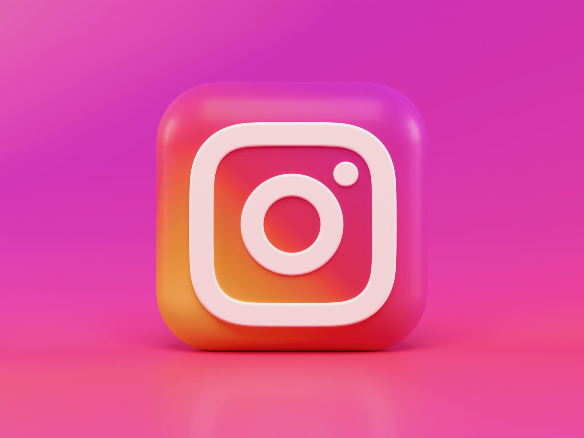 A 3-D rendering of the instagram logo on a bright purple and purple gradient background