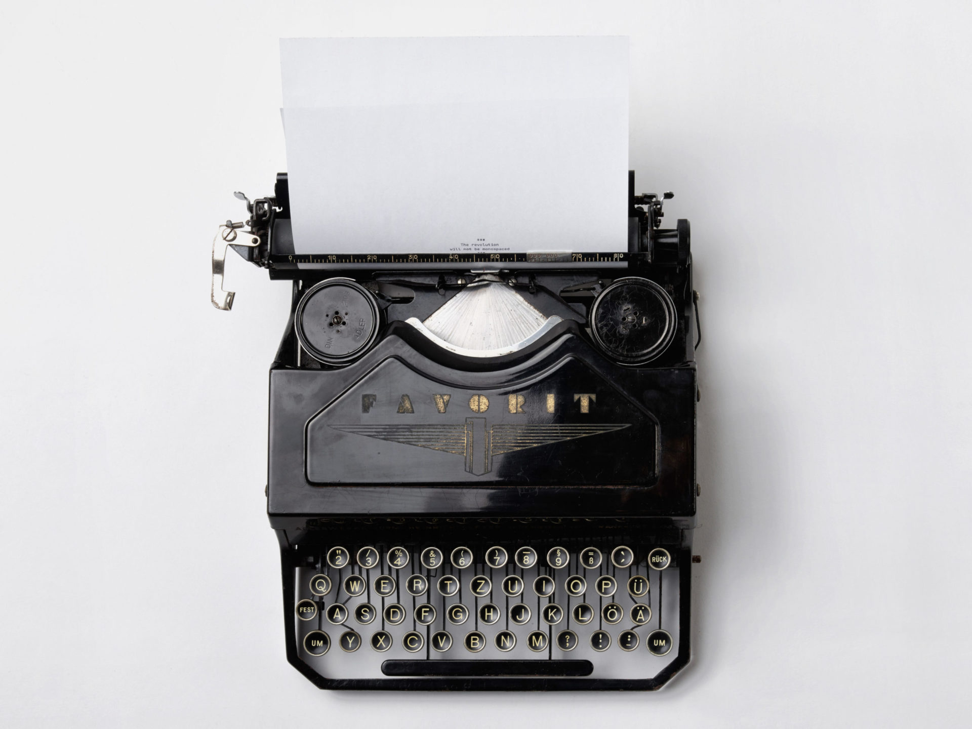 A black typewriter sitting on a white background with paper in it