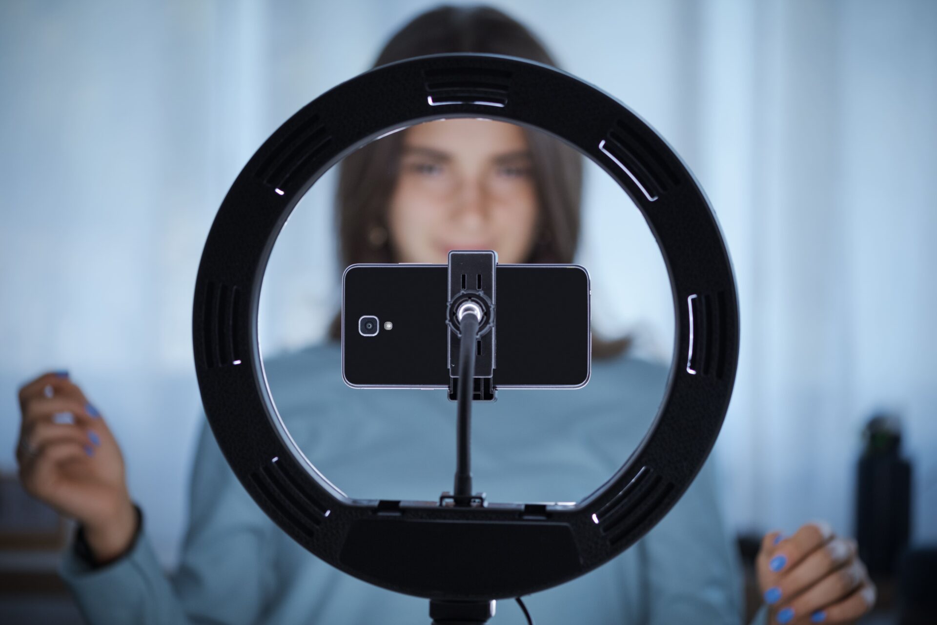 Young woman filming video with ring light
